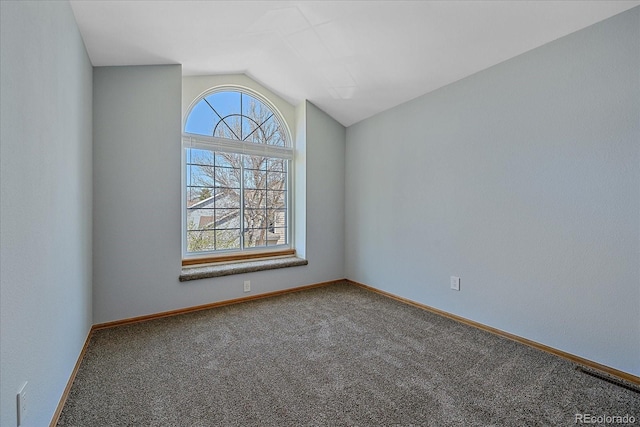 empty room with carpet floors, vaulted ceiling, and baseboards
