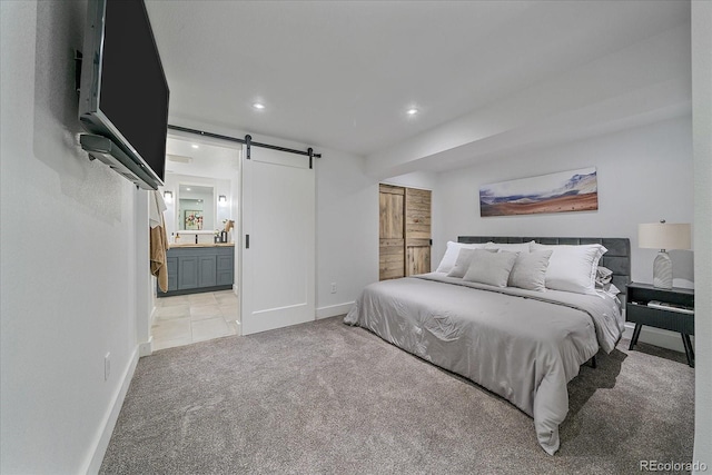 bedroom with light carpet, a barn door, recessed lighting, baseboards, and connected bathroom