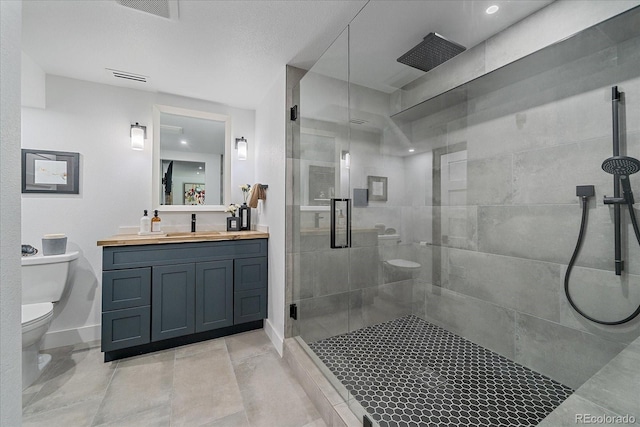 full bathroom with toilet, a stall shower, vanity, and baseboards
