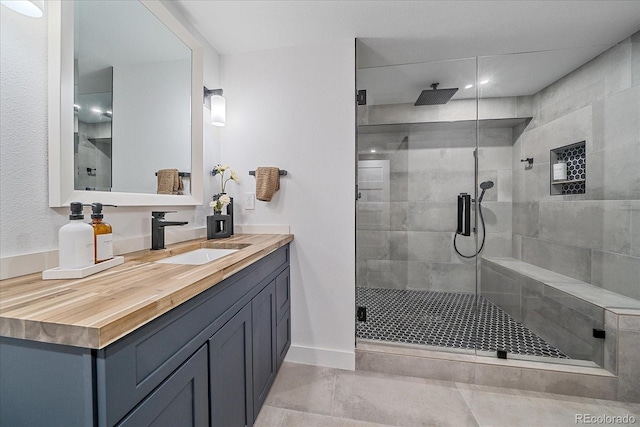 bathroom with a shower stall, vanity, and baseboards