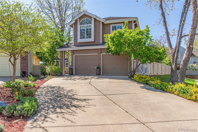 traditional-style home featuring a garage, driveway, brick siding, and fence