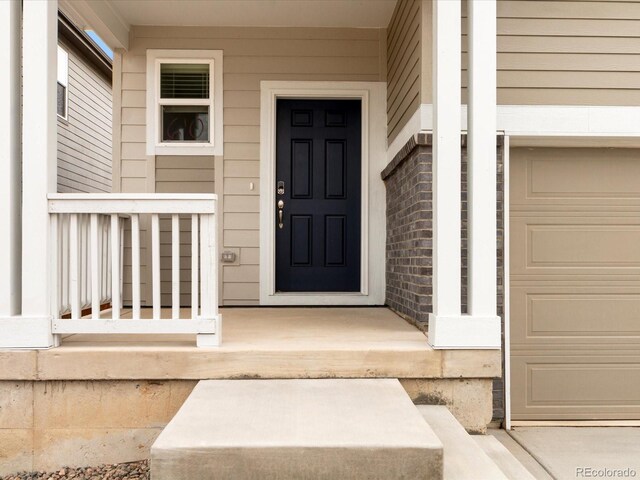 property entrance with a porch and brick siding
