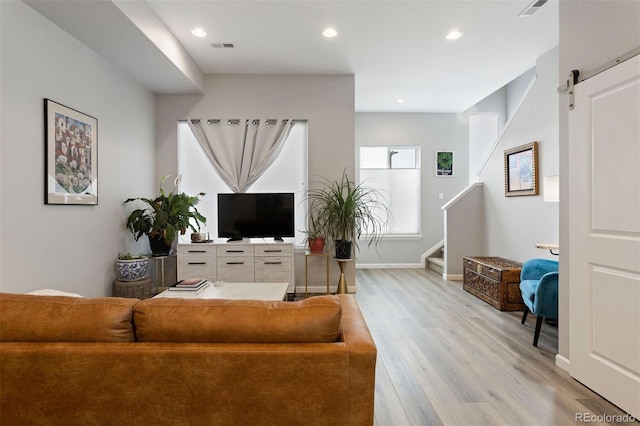 living room featuring a barn door and light hardwood / wood-style flooring