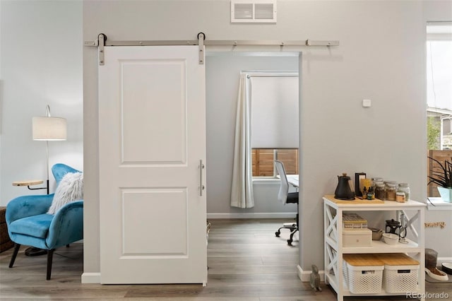 home office with a barn door and hardwood / wood-style floors