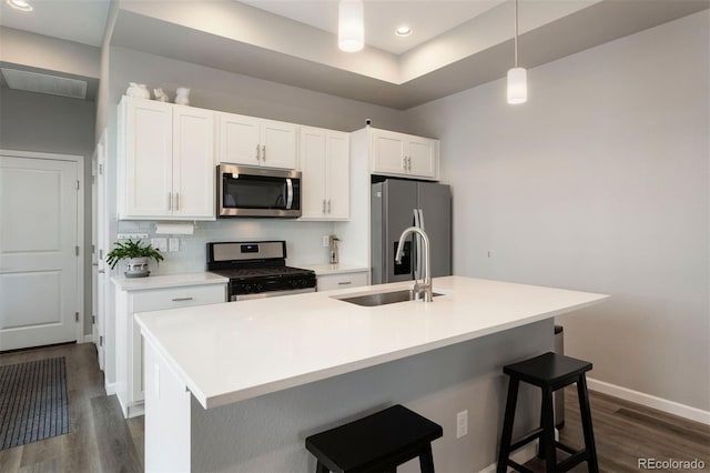 kitchen featuring a kitchen bar, appliances with stainless steel finishes, a center island with sink, and sink