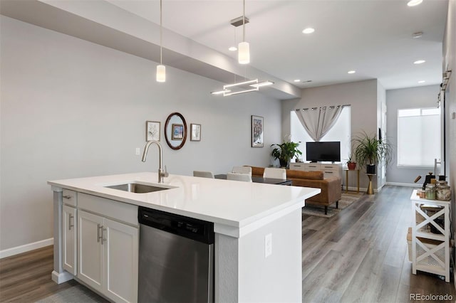 kitchen with stainless steel dishwasher, sink, decorative light fixtures, a center island with sink, and white cabinets