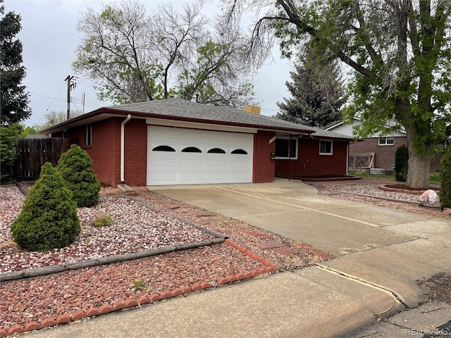 view of front facade featuring brick siding, an attached garage, concrete driveway, and fence