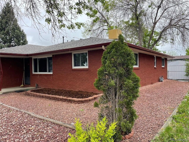 view of home's exterior with brick siding and roof with shingles