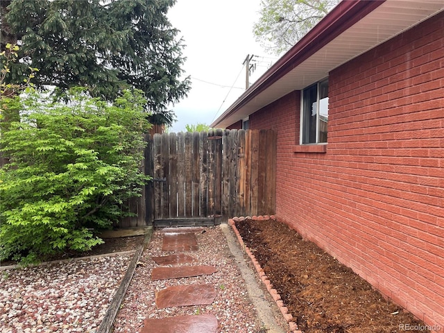 view of side of home with fence and brick siding