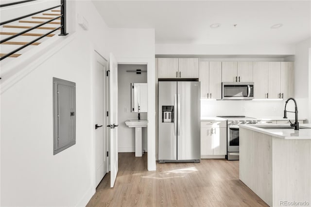 kitchen with sink, stainless steel appliances, electric panel, and light hardwood / wood-style flooring