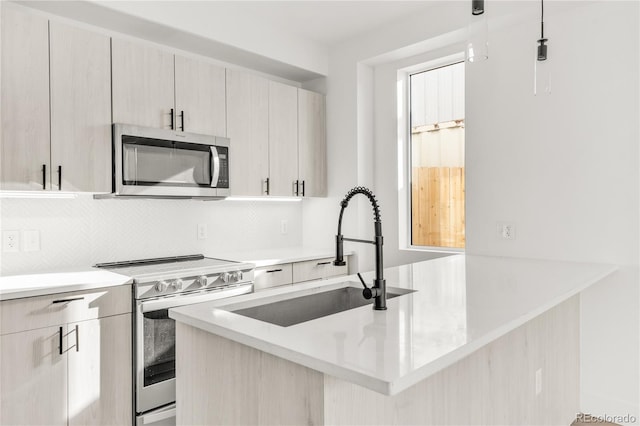 kitchen with kitchen peninsula, appliances with stainless steel finishes, tasteful backsplash, sink, and decorative light fixtures