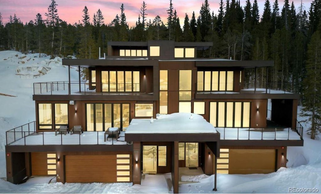 310 N Fuller Placer Rd, Breckenridge, CO 80424 - snow covered rear of property featuring a balcony, a garage, and a view of trees