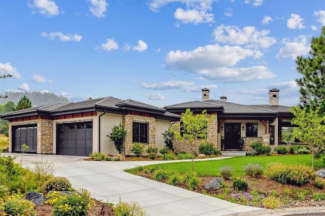 prairie-style house featuring a garage, stone siding, concrete driveway, and a front yard