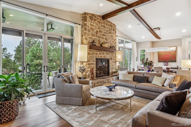 living room with beamed ceiling, a wealth of natural light, a stone fireplace, and hardwood / wood-style floors