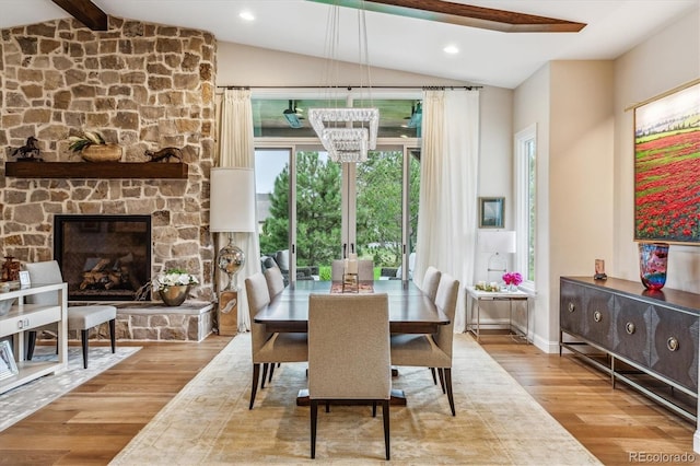 dining room featuring vaulted ceiling with beams, recessed lighting, a notable chandelier, a fireplace, and wood finished floors