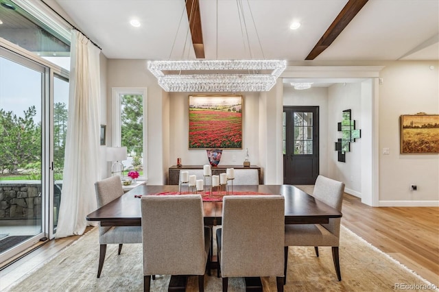 dining space featuring beamed ceiling, light wood-type flooring, and an inviting chandelier