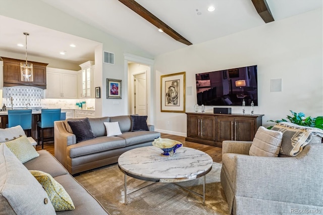 living area with vaulted ceiling with beams, recessed lighting, visible vents, baseboards, and light wood-style floors