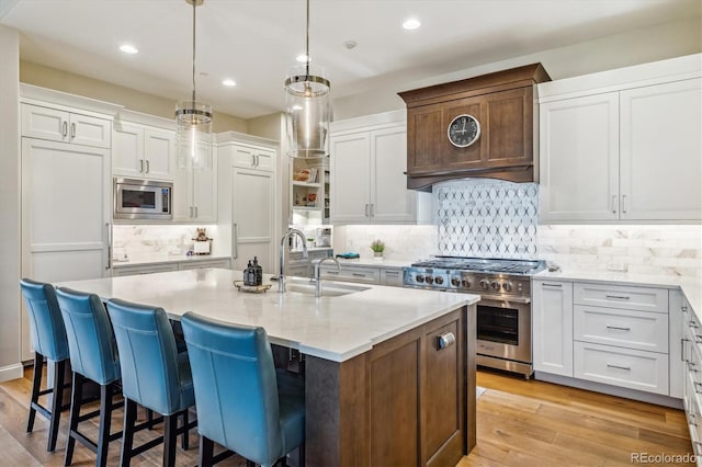 kitchen featuring appliances with stainless steel finishes, an island with sink, a sink, and white cabinetry