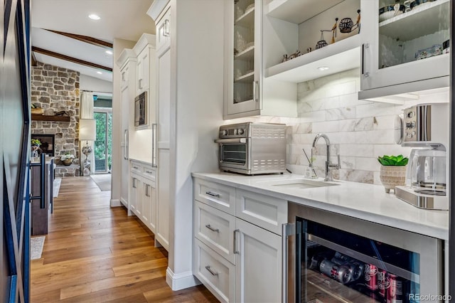 kitchen featuring glass insert cabinets, beverage cooler, light countertops, and white cabinetry