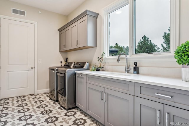 laundry room with cabinets, washing machine and clothes dryer, light tile patterned floors, and sink