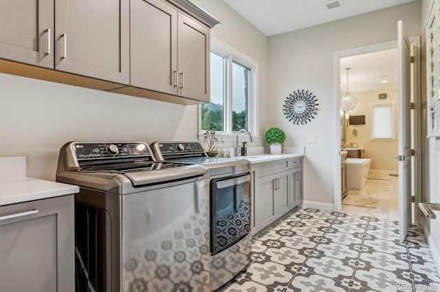 clothes washing area with crown molding, light tile patterned floors, cabinets, sink, and independent washer and dryer