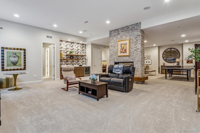 living room with a stone fireplace, recessed lighting, beverage cooler, light colored carpet, and visible vents