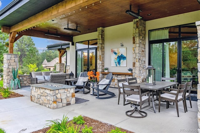 view of patio with outdoor dining area and an outdoor living space with a fire pit