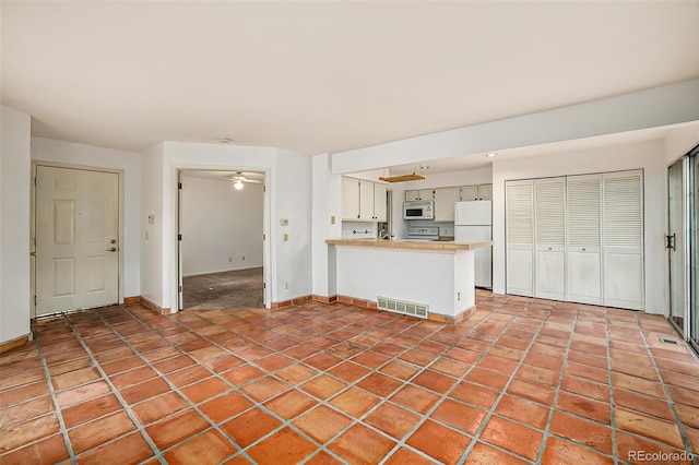 unfurnished living room featuring ceiling fan and tile floors