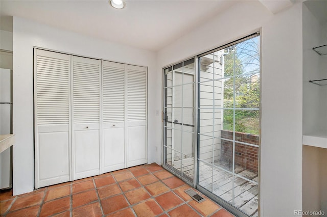 interior space featuring stainless steel refrigerator, tile floors, and a closet