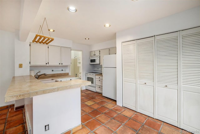 kitchen featuring white appliances, kitchen peninsula, sink, and dark tile flooring