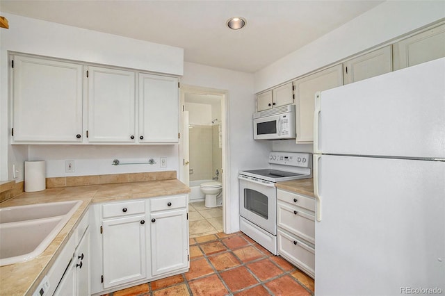 kitchen featuring sink, white appliances, and light tile flooring