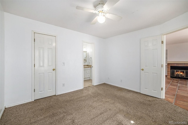 unfurnished bedroom with ensuite bathroom, ceiling fan, carpet flooring, and a fireplace