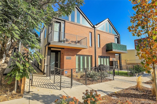 view of front facade featuring a fenced front yard, brick siding, a balcony, and a gate