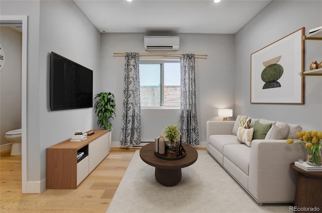 living area with baseboards, light wood-style floors, and a wall unit AC