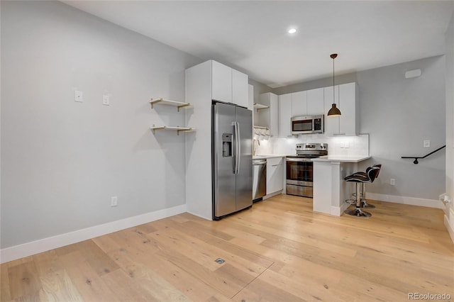 kitchen with open shelves, a kitchen breakfast bar, appliances with stainless steel finishes, a peninsula, and light countertops