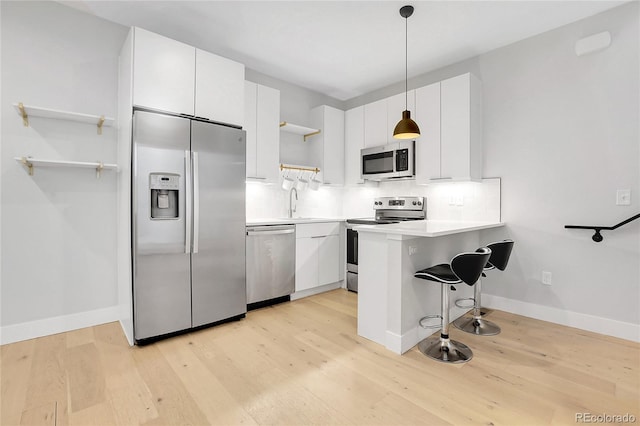 kitchen featuring open shelves, stainless steel appliances, backsplash, and light wood-style flooring