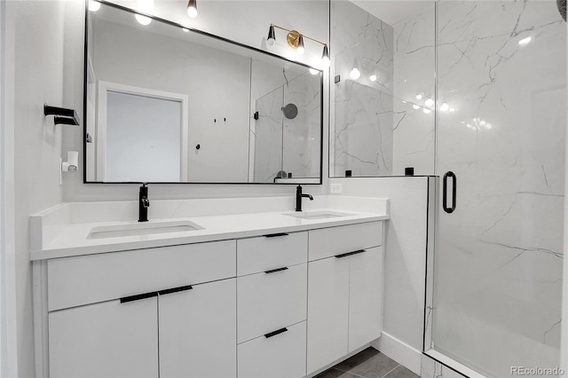 full bath with double vanity, a marble finish shower, and a sink