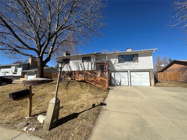 bi-level home with driveway, an attached garage, and fence