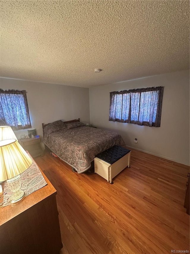 bedroom with wood finished floors and a textured ceiling