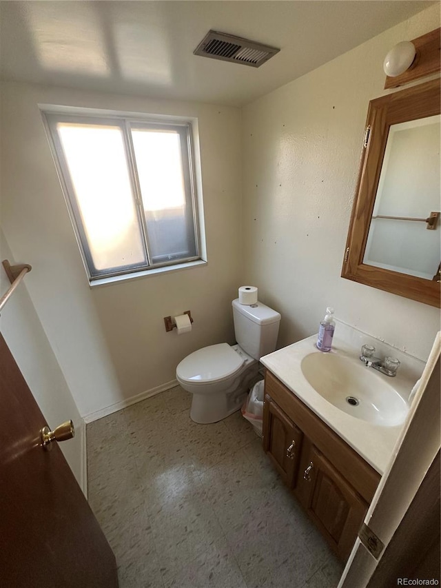 bathroom featuring vanity, baseboards, visible vents, tile patterned floors, and toilet