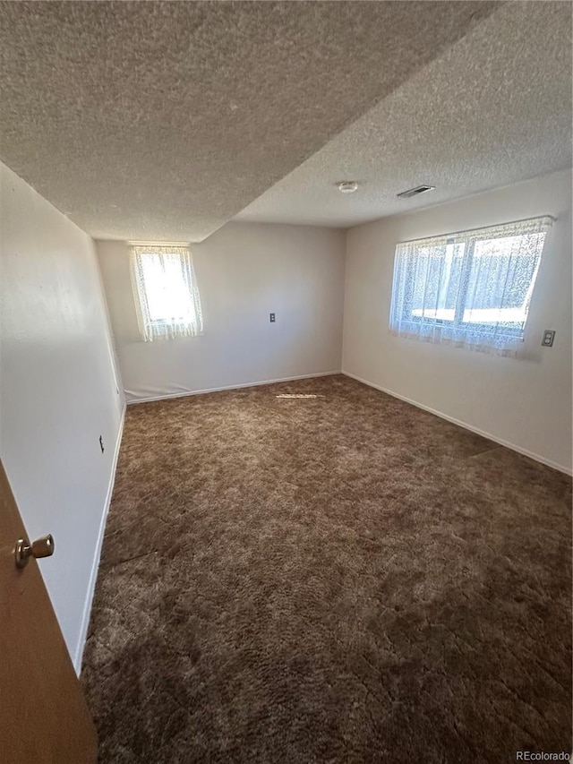 empty room featuring baseboards, carpet flooring, a textured ceiling, and visible vents