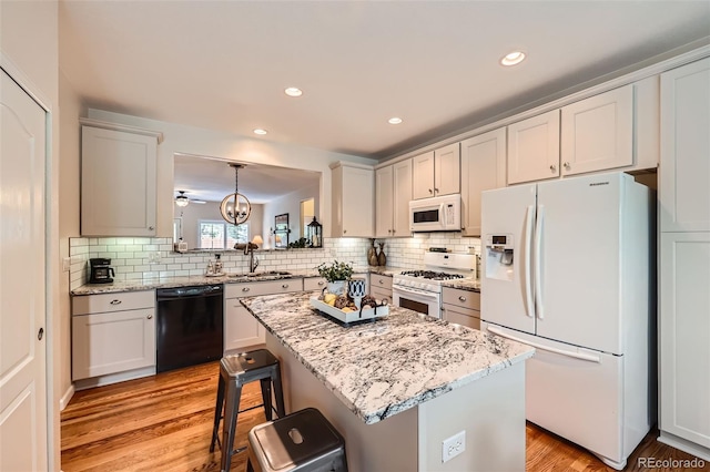 21107 Hawthorne Ln, Parker, CO 80138 - kitchen featuring white appliances, light wood-style floors, decorative backsplash, a breakfast bar area, and recessed lighting