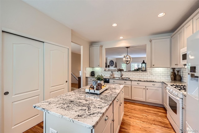 21107 Hawthorne Ln, Parker, CO 80138 - kitchen with white appliances, tasteful backsplash, light wood finished floors, a center island, and recessed lighting