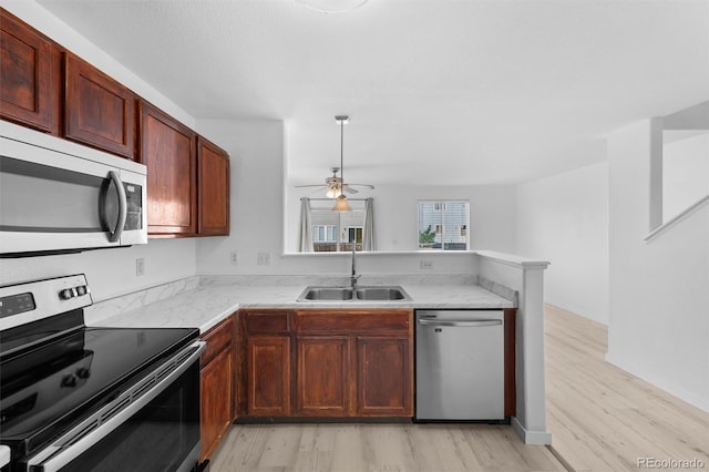 kitchen featuring stainless steel appliances, kitchen peninsula, light hardwood / wood-style floors, and sink