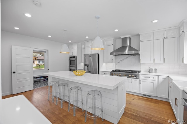 5853 S Havana Ct, Englewood, CO 80111 - kitchen featuring appliances with stainless steel finishes, wall chimney exhaust hood, white cabinets, a center island, and backsplash