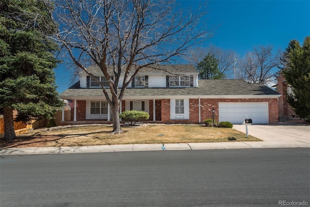 traditional-style house with driveway, brick siding, an attached garage, and fence