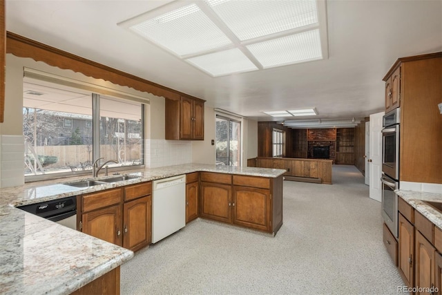 kitchen featuring open floor plan, a fireplace, a peninsula, white dishwasher, and a sink