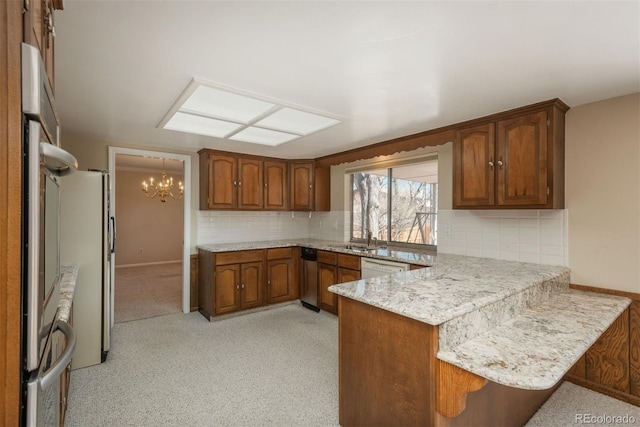 kitchen with a peninsula, a notable chandelier, tasteful backsplash, and brown cabinets