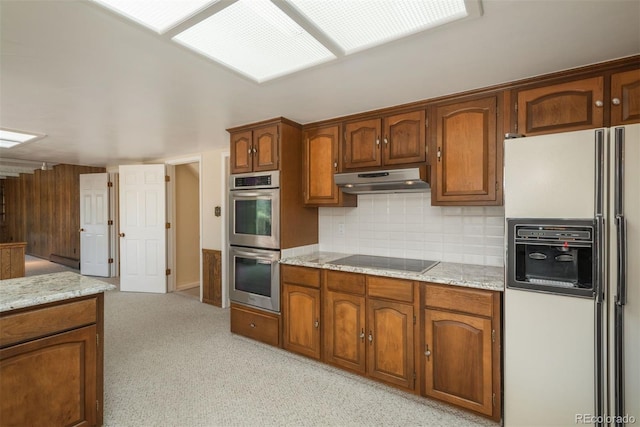 kitchen with decorative backsplash, under cabinet range hood, white fridge with ice dispenser, double oven, and black electric cooktop