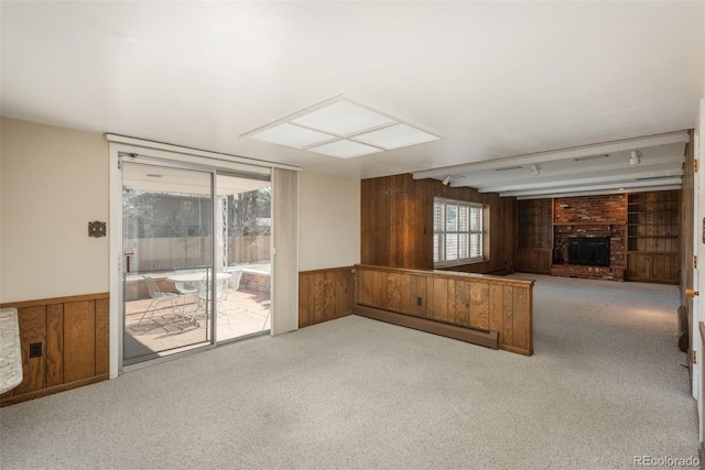 unfurnished living room featuring wood walls, a baseboard heating unit, and carpet